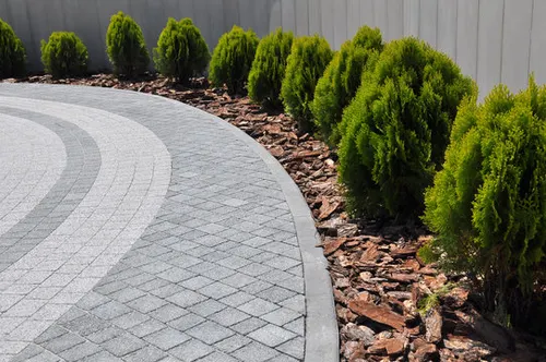 Stone walkway bordered by shrubs and mulch